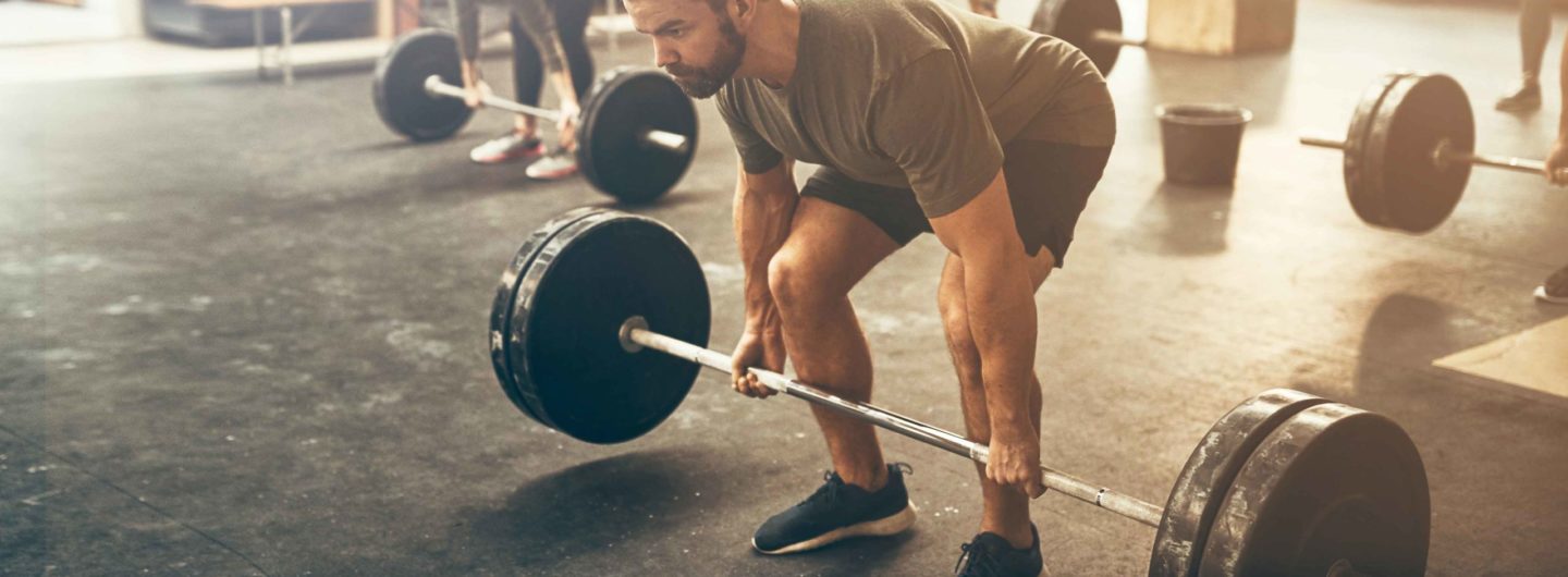 Man lifting a barbell doing a strength and muscle workout