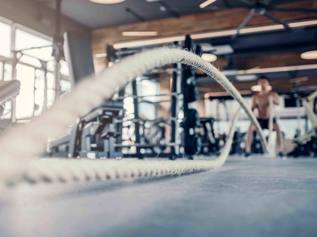 Man using battle ropes in gym to burn body fat