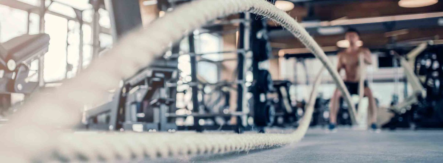 Man using battle ropes in gym to burn body fat