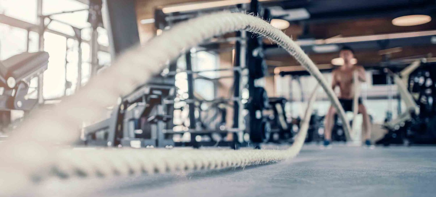 Man using battle ropes in gym to burn body fat